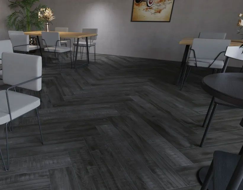 A modern, minimalist restaurant dining room with dark wood flooring in a herringbone pattern and light-colored chairs.