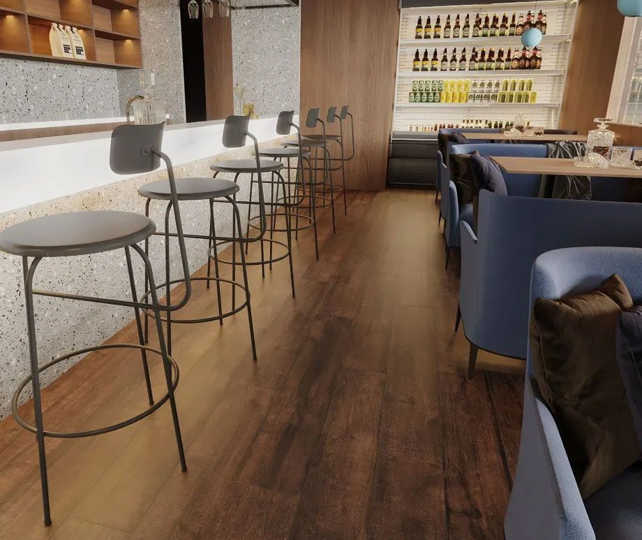 Modern bar interior with a row of grey stools at a white counter, wooden floors, and blue upholstered lounge seating.