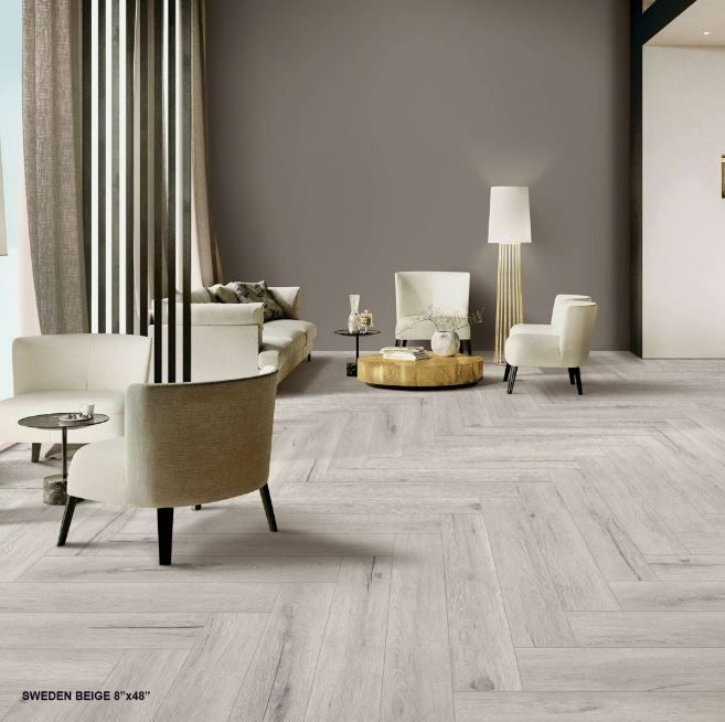 A minimalist living room with beige furniture, a wooden coffee table, and light wood flooring in a herringbone pattern.