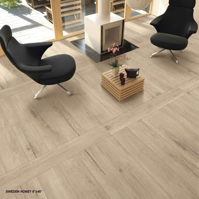 Two modern black chairs sit on light wood-look tiled flooring in a living room with a fireplace and wooden stool.