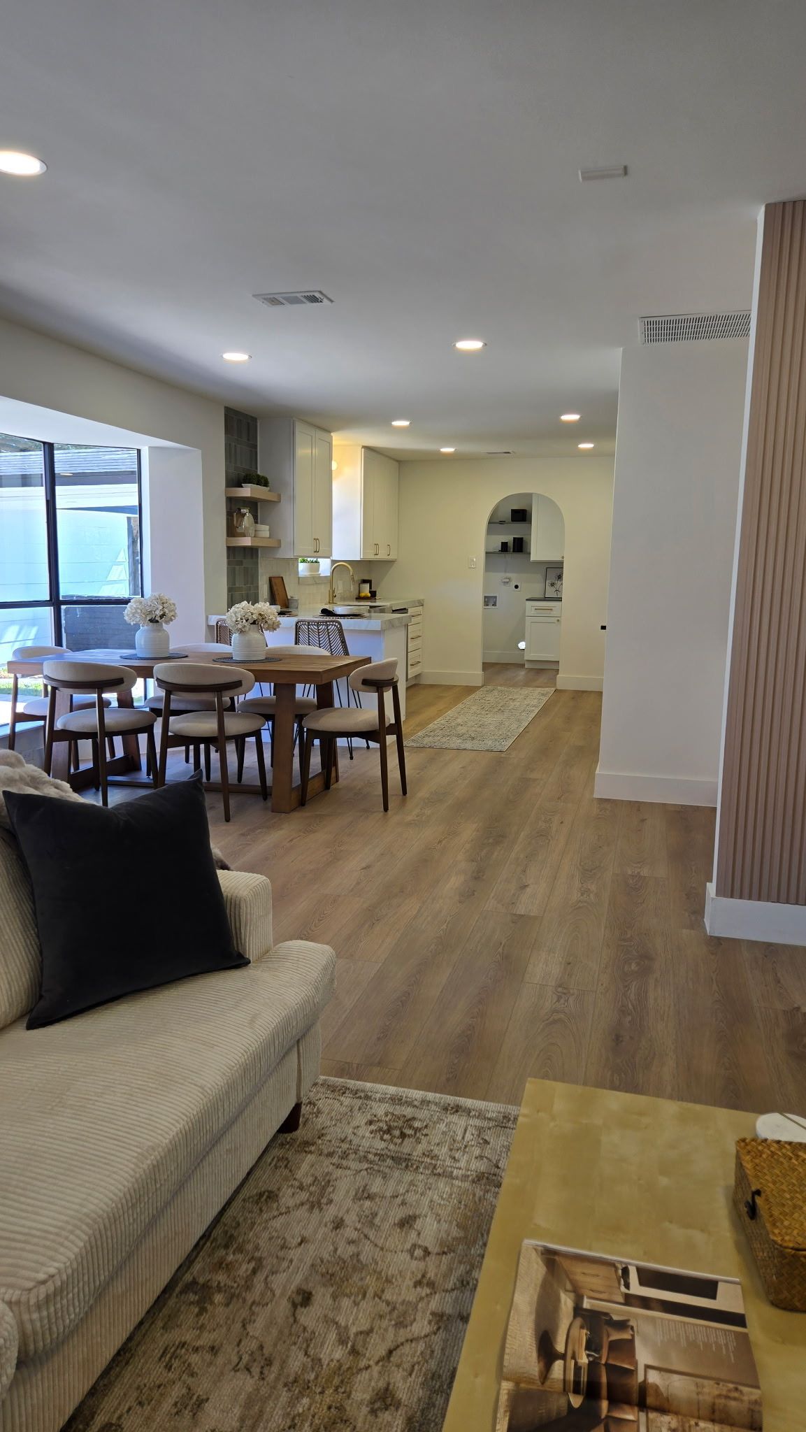 Open-concept interior featuring a living area with a couch, a dining table with chairs, and a kitchen in the background.