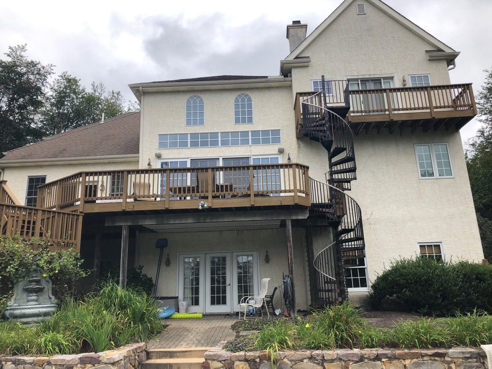 A large white house with a spiral staircase and a large deck.