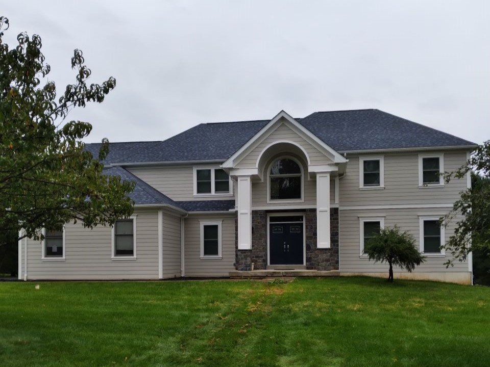 A large house sits in the middle of a lush green field