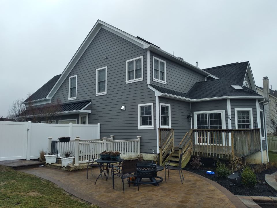 A large gray house with a white fence and a deck