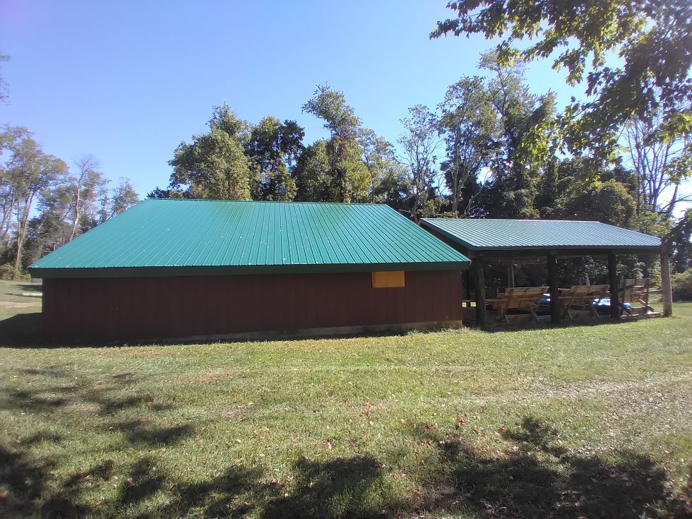 A brick building with a green roof next to a pavilion