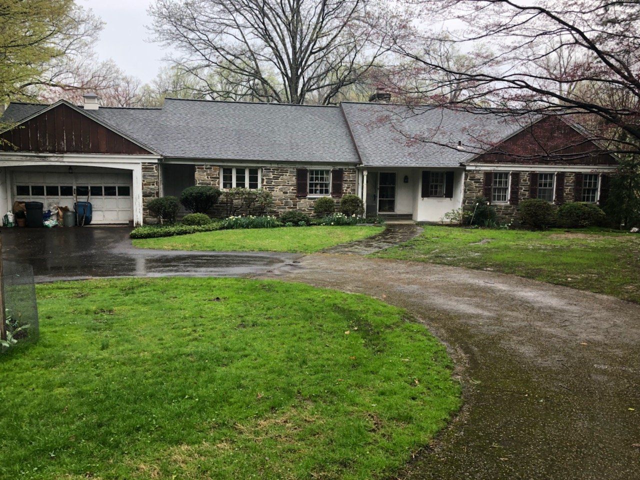 A large house with a lush green lawn and a driveway leading to it.