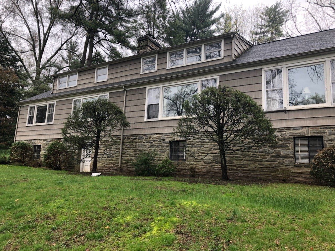A large house with a lot of windows is sitting on top of a lush green hillside.