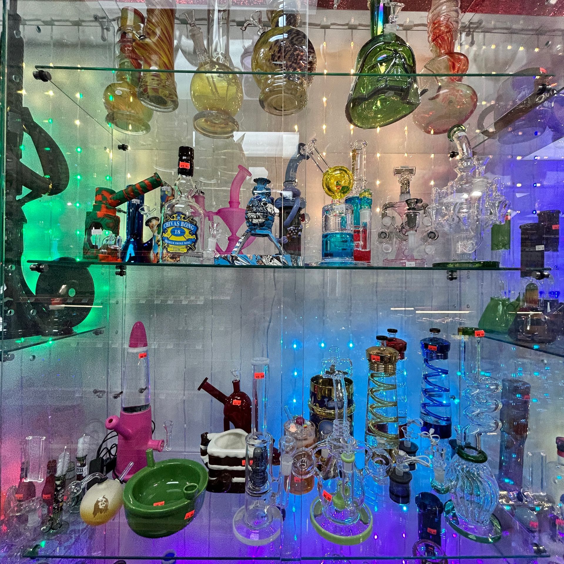 Glass smoking pipes and bongs displayed inside a brightly lit store cabinet.