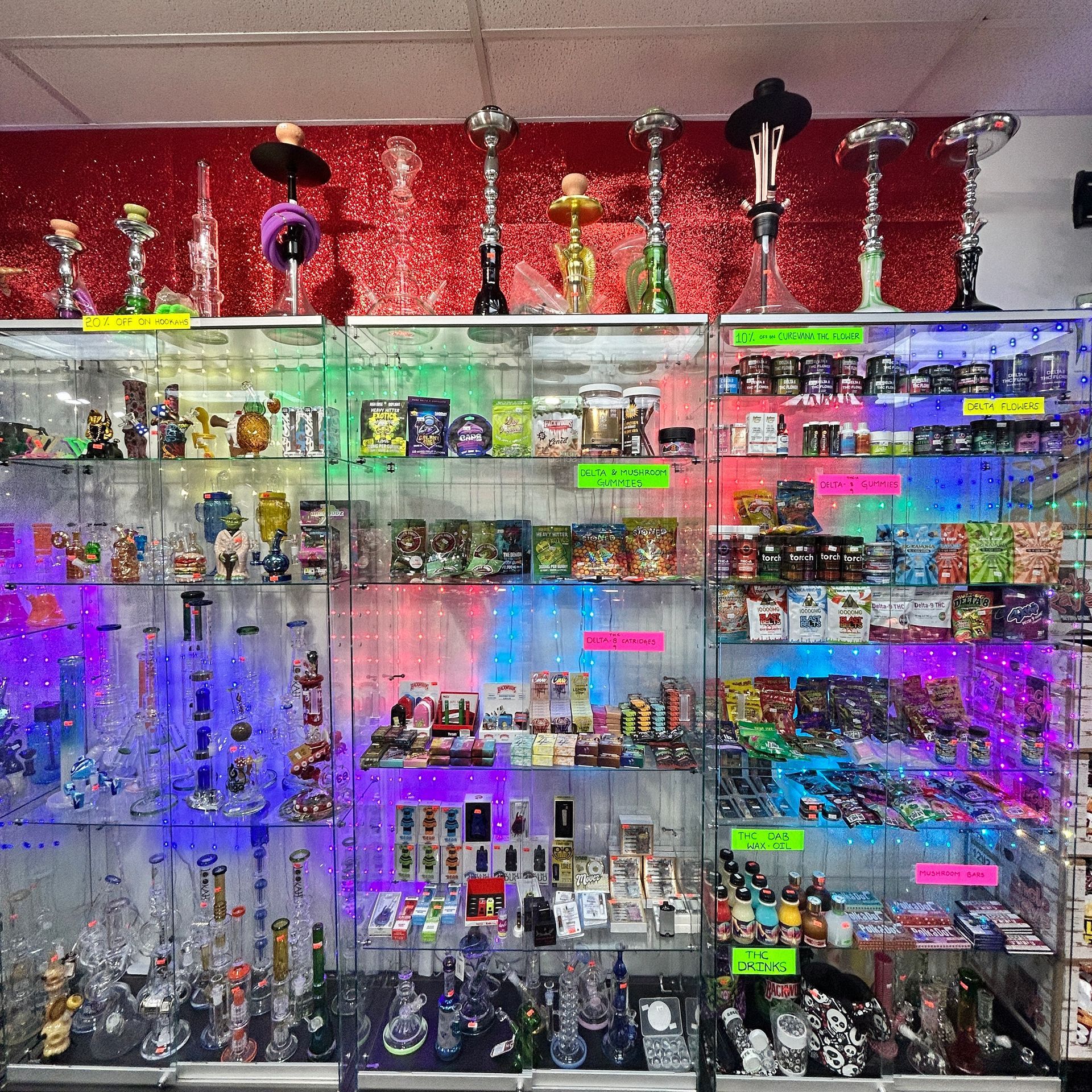 Shelves of glass smoking pipes and accessories in a retail store. Back wall has hookahs.