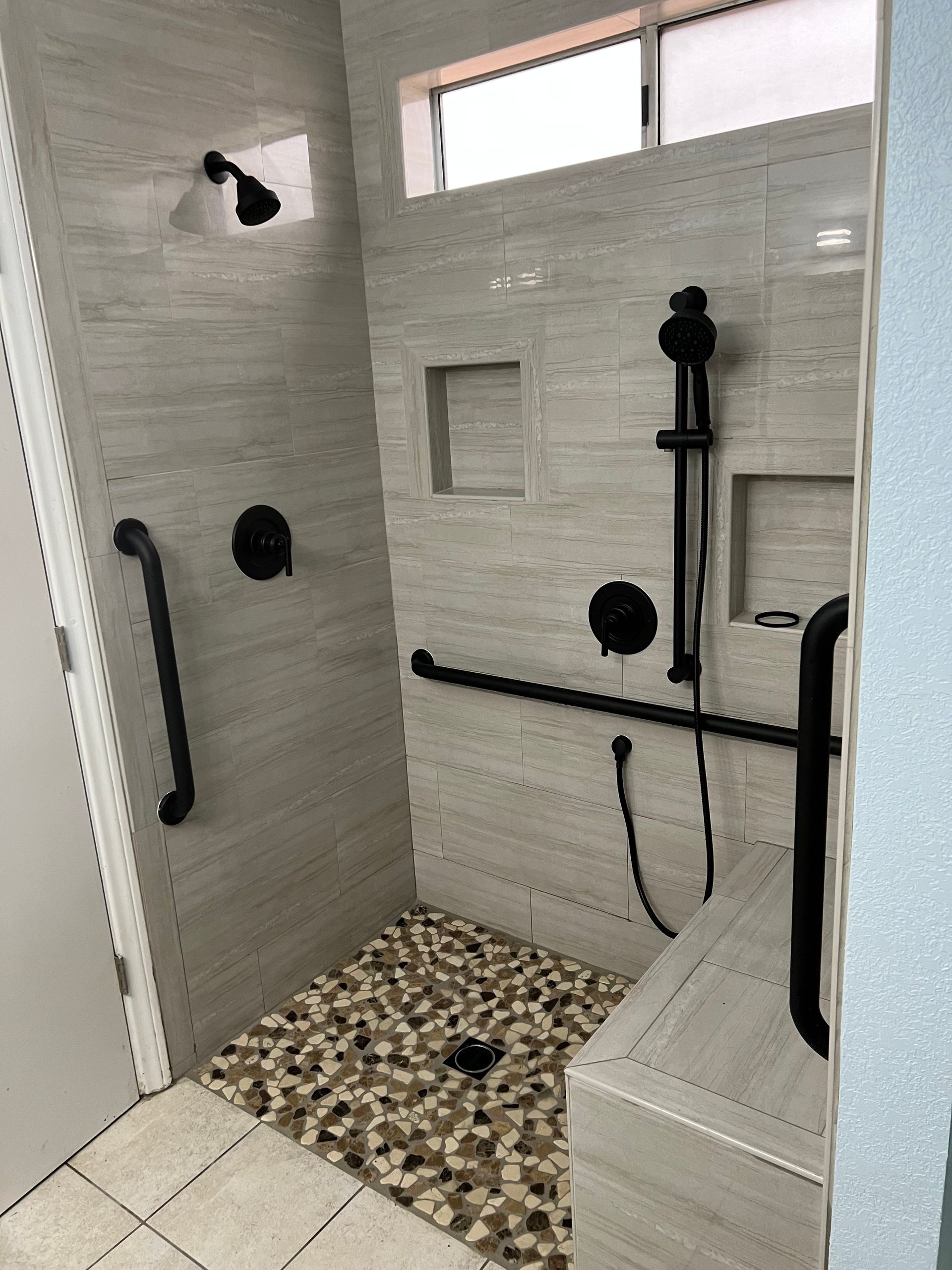 A bathroom with a walk in shower and a window.