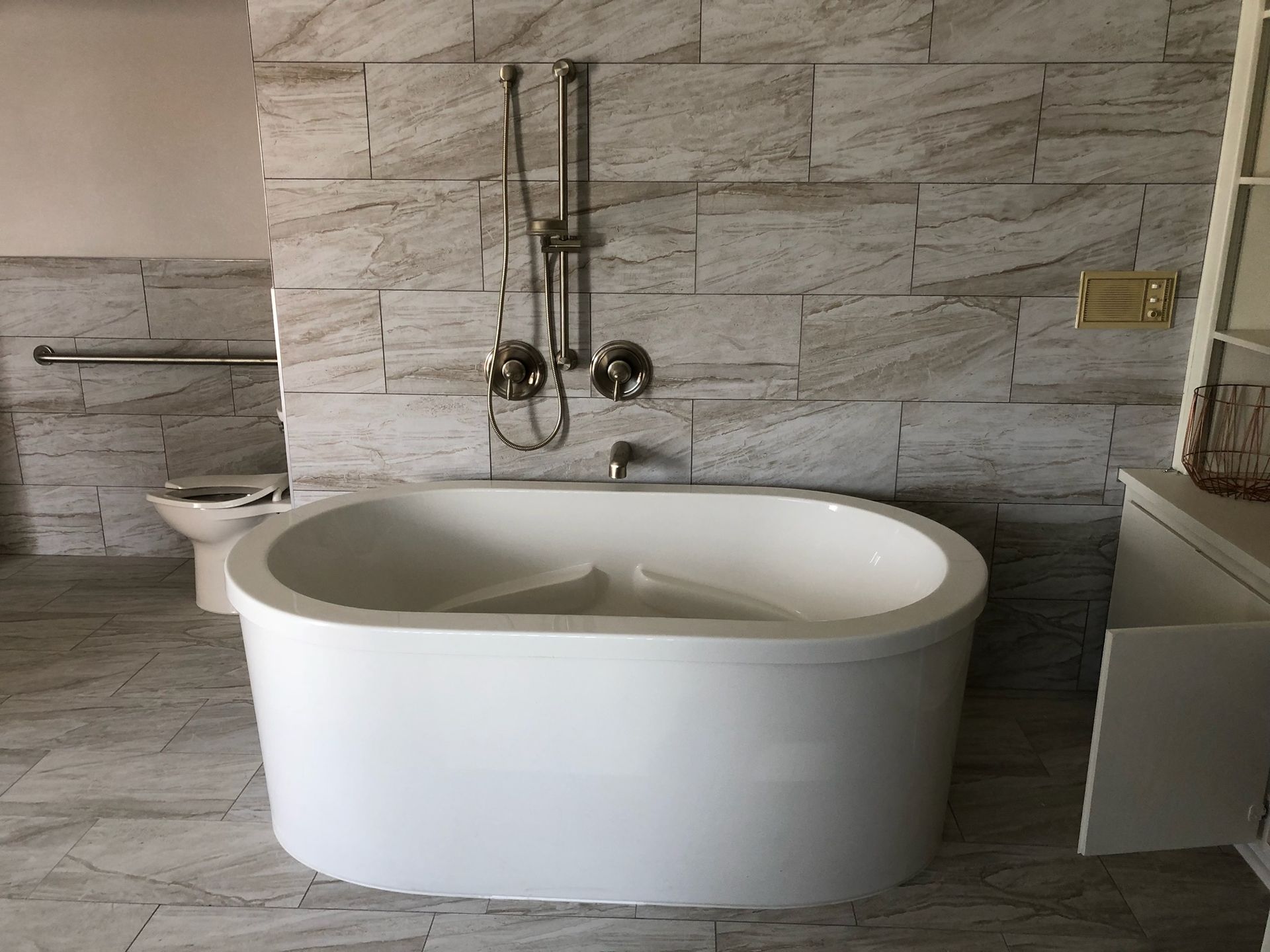 A white bathtub is sitting in a bathroom next to a toilet.