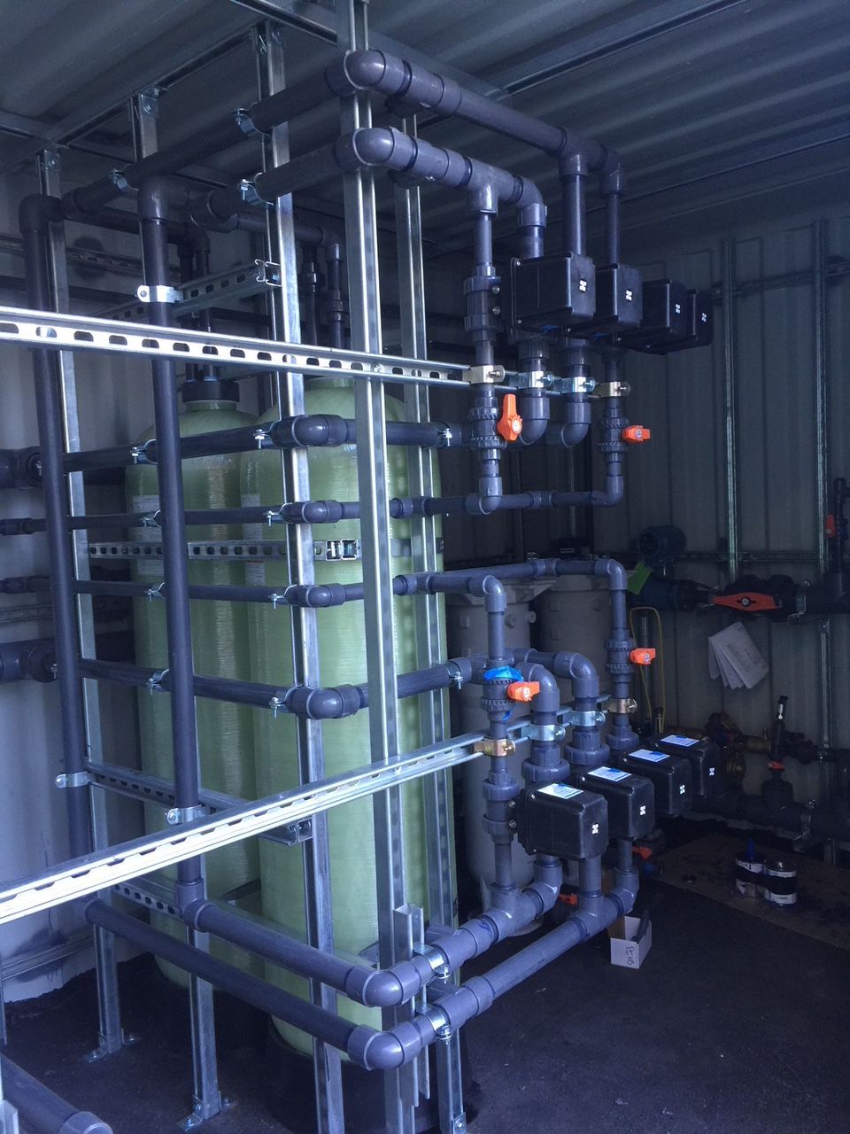 A room filled with lots of pipes and a green tank.