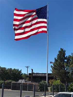 A large American flag is flying in front of a building
