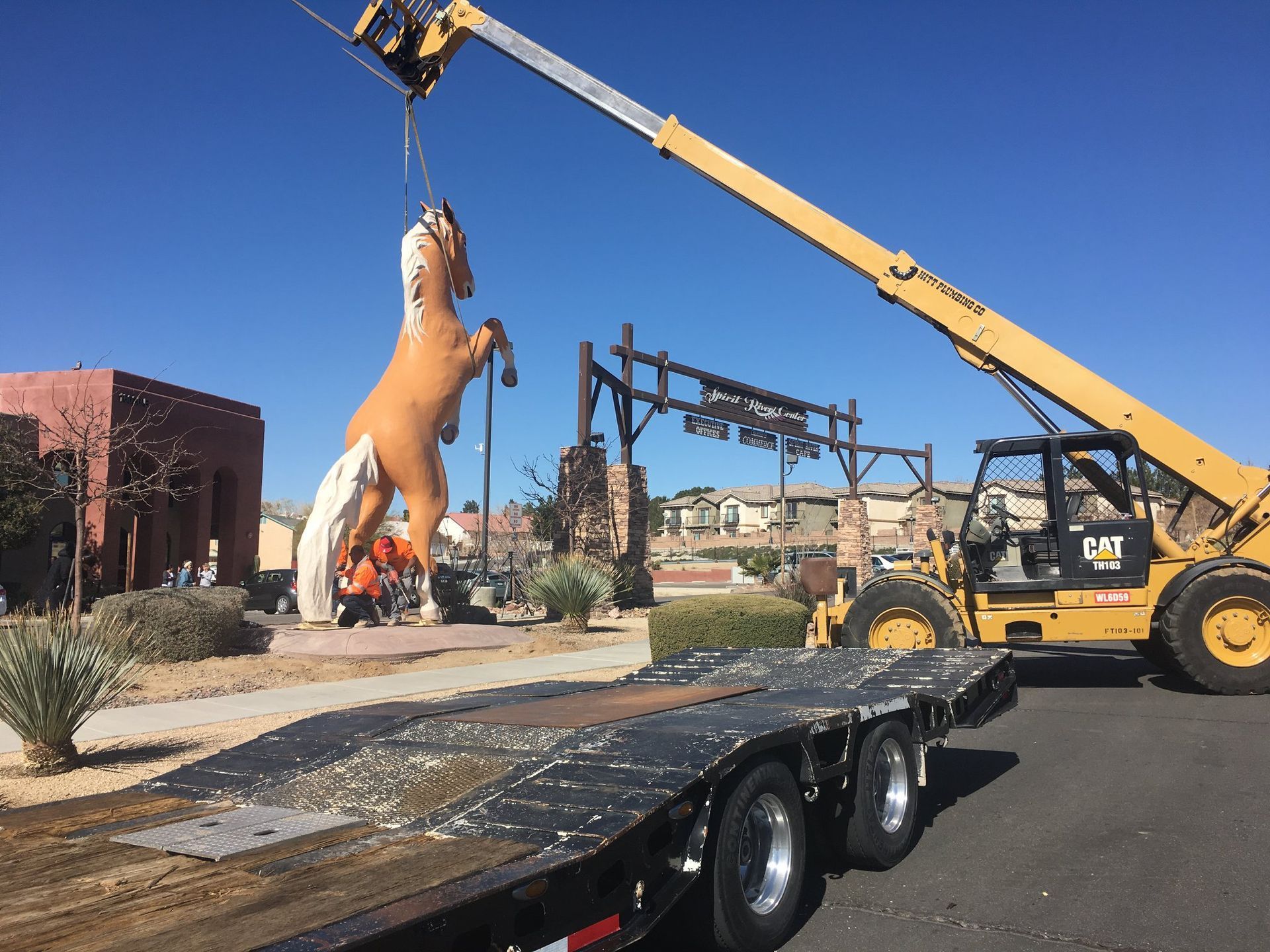 A large statue of a horse is being lifted by a crane.