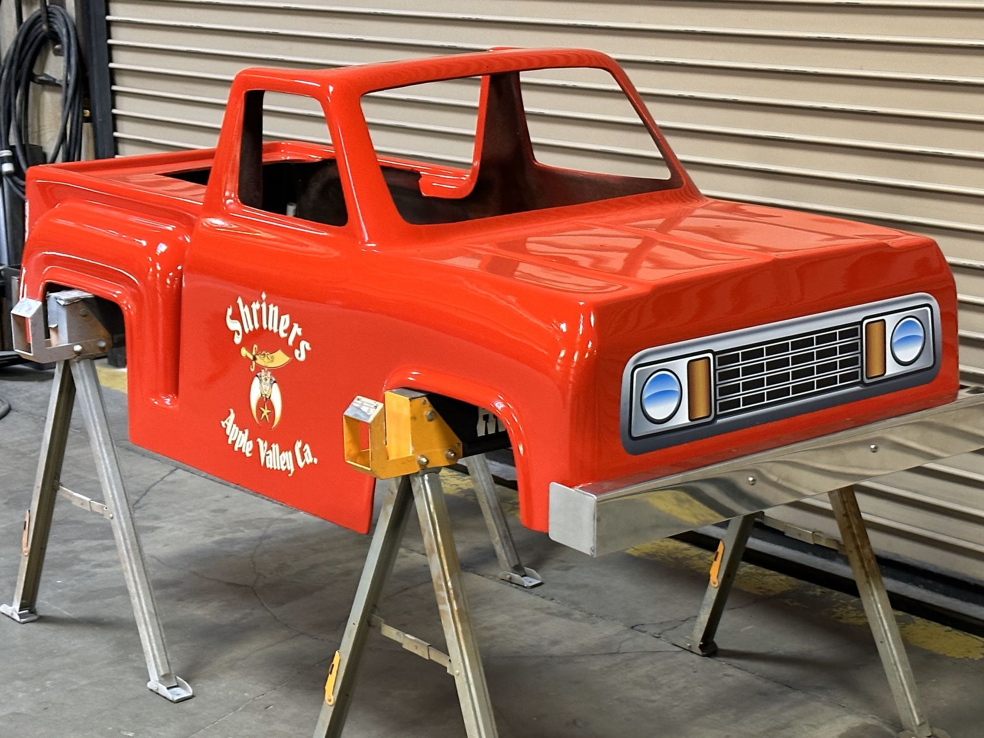 A red truck body is sitting on a wooden stand.
