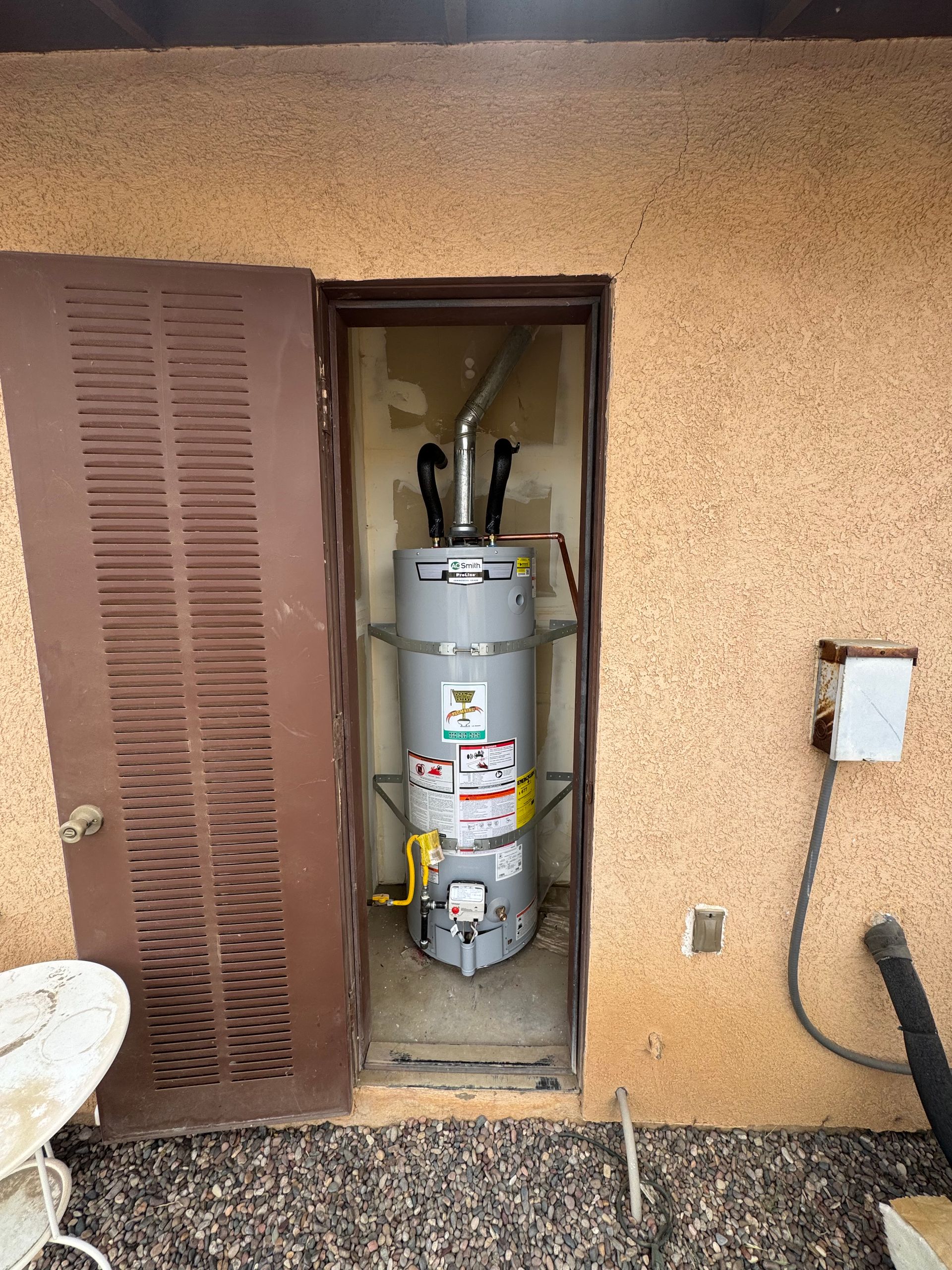 A water heater is sitting in a doorway on the side of a building.