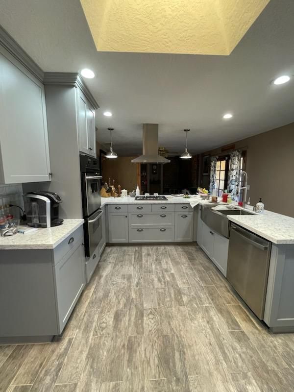 A kitchen with white cabinets, stainless steel appliances, a sink, and a skylight.
