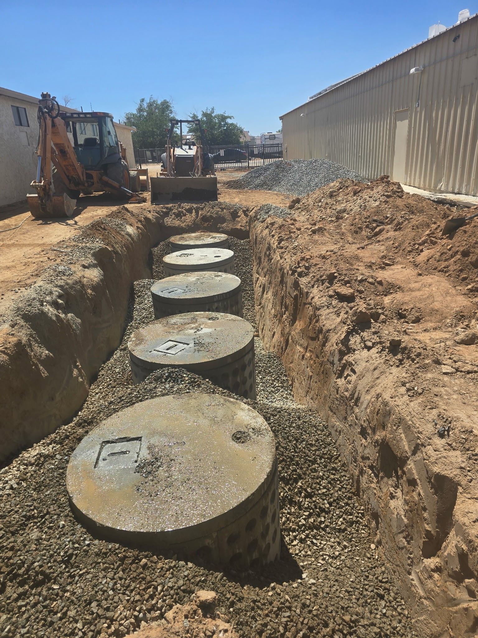 A row of septic tanks are being installed in a trench.
