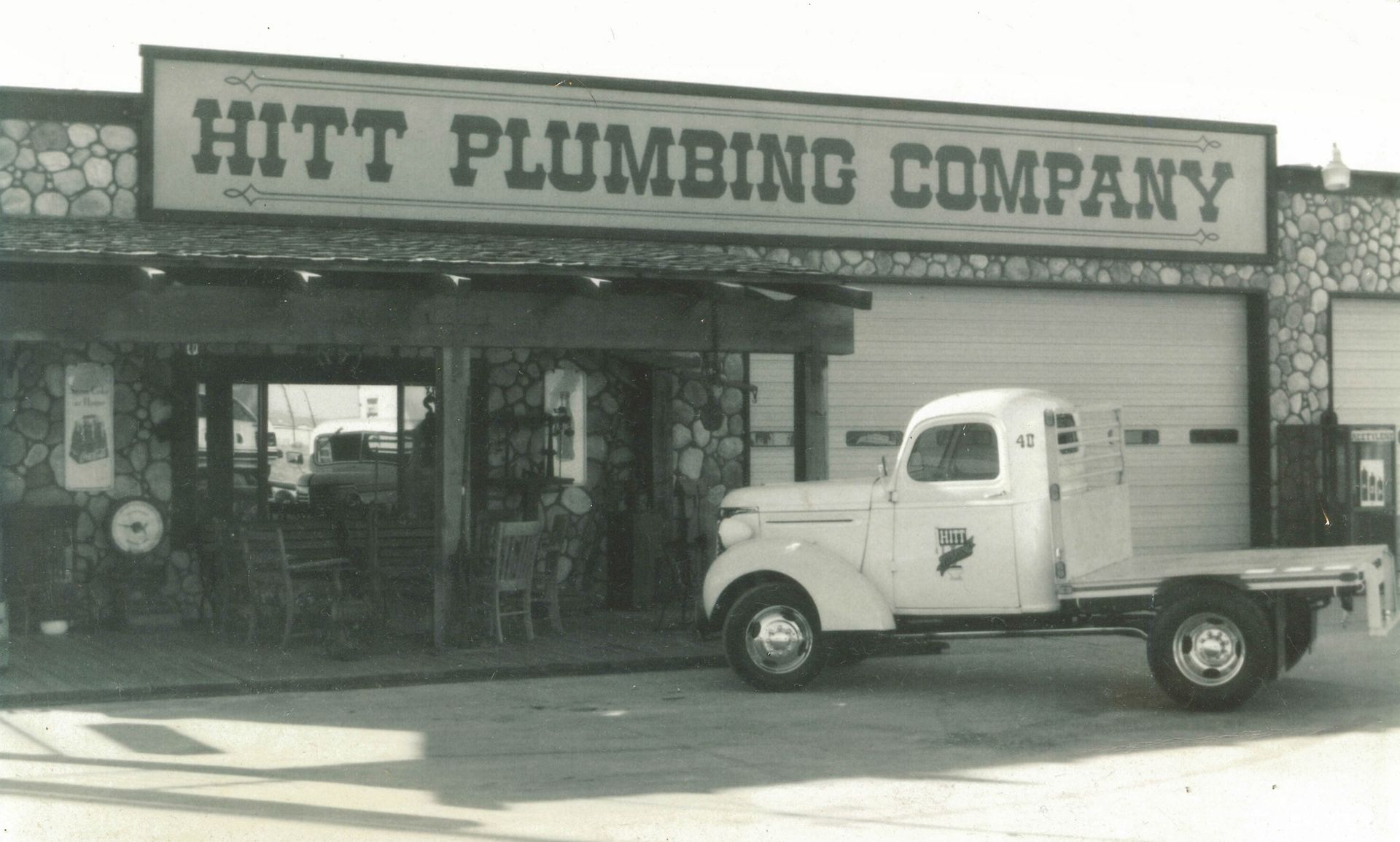 A truck is parked in front of a building that says hitt plumbing company.