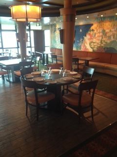 Restaurant interior with round table set for dining, chairs, and colorful mural on the wall.