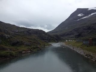 River flowing between mountains under a cloudy sky.