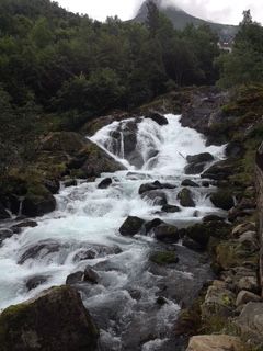 Rushing waterfall cascading over mossy rocks in a lush, green mountain setting.