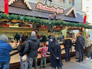 A Christmas market food stall with a line of people waiting to order.