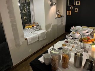 Breakfast buffet with fruit, cereal, and drinks set up in a room with a window.