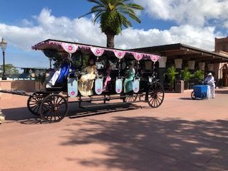 Horse-drawn carriage with riders in Epcot's Morocco. Overhead canopy. A person pushes a vendor cart.