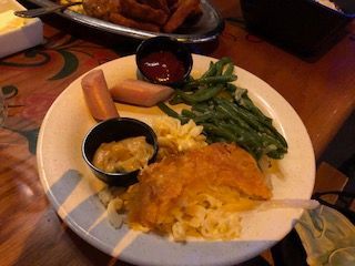 Plate of food with macaroni and cheese, vegetables, and sausage.