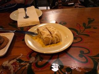 Cake on a plate, two slices, covered in frosting. Served on a wooden table with floral designs.