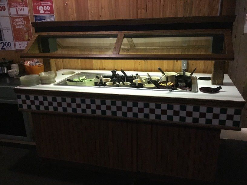 A salad bar in a restaurant with a checkered counter top.