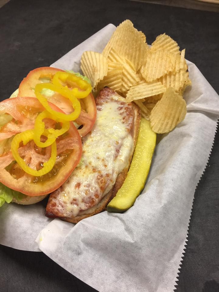 A sandwich with tomatoes peppers and chips in a basket