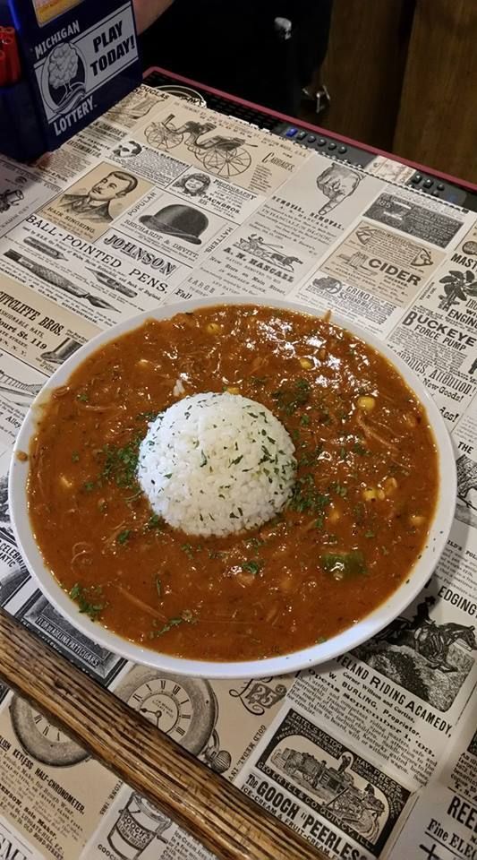 A bowl of gumbo with rice on top of it on a table.