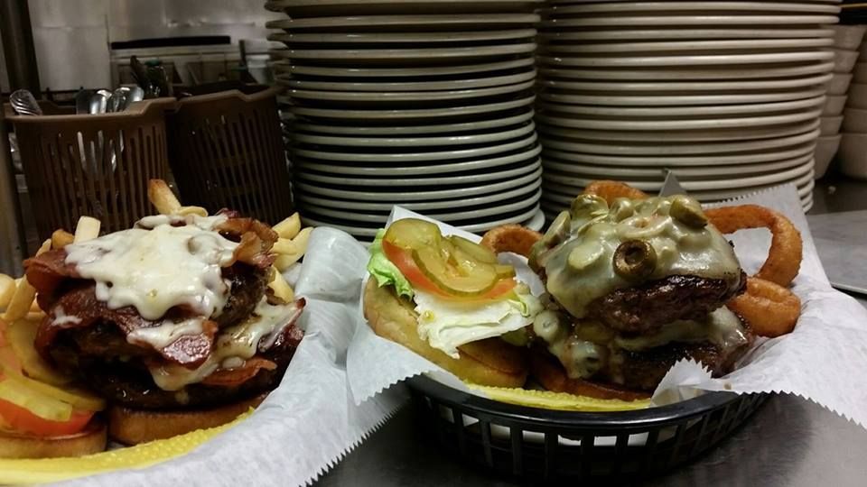 Two hamburgers and french fries are in baskets on a table.