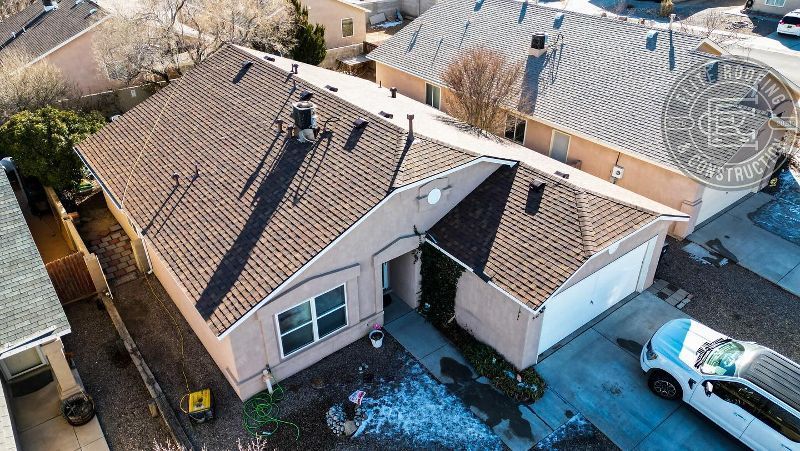 Overhead view of a house with a brown roof and a white garage door; a car is parked in the driveway.