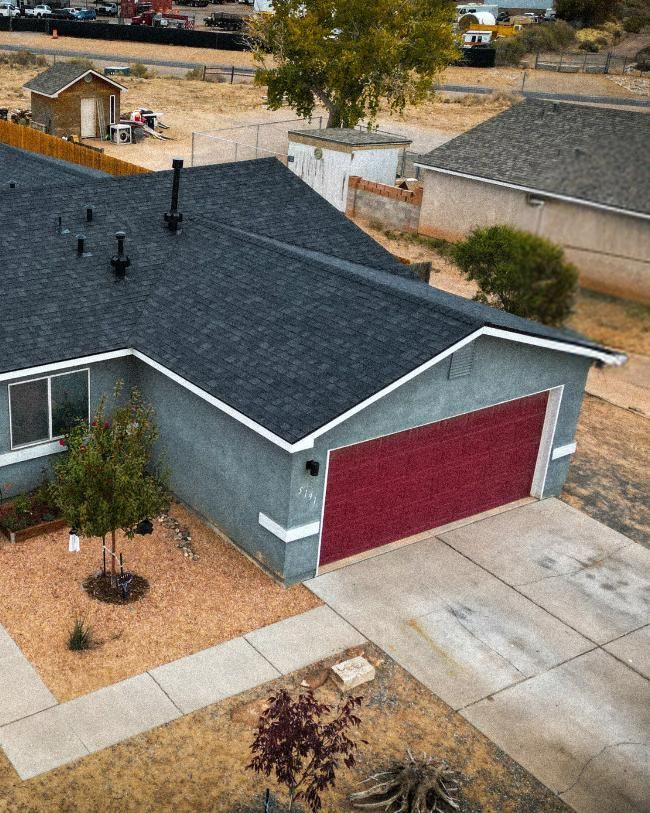 Gray house with dark gray roof, red garage door, and tan driveway.