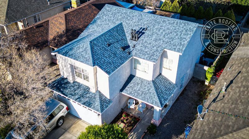 Aerial view of a white house with a gray roof and a car parked in the driveway.