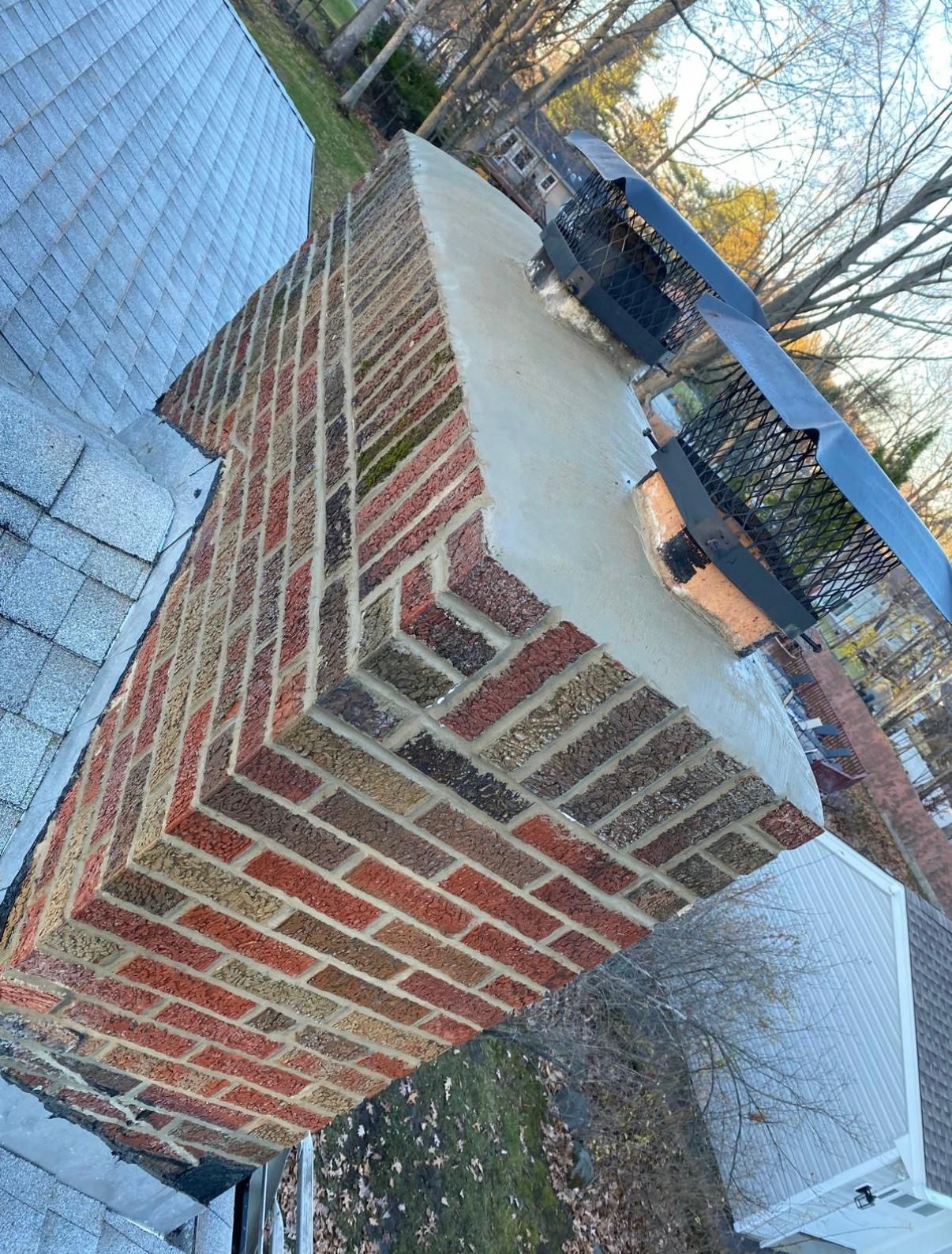 Brick chimney on a roof with a metal cap.