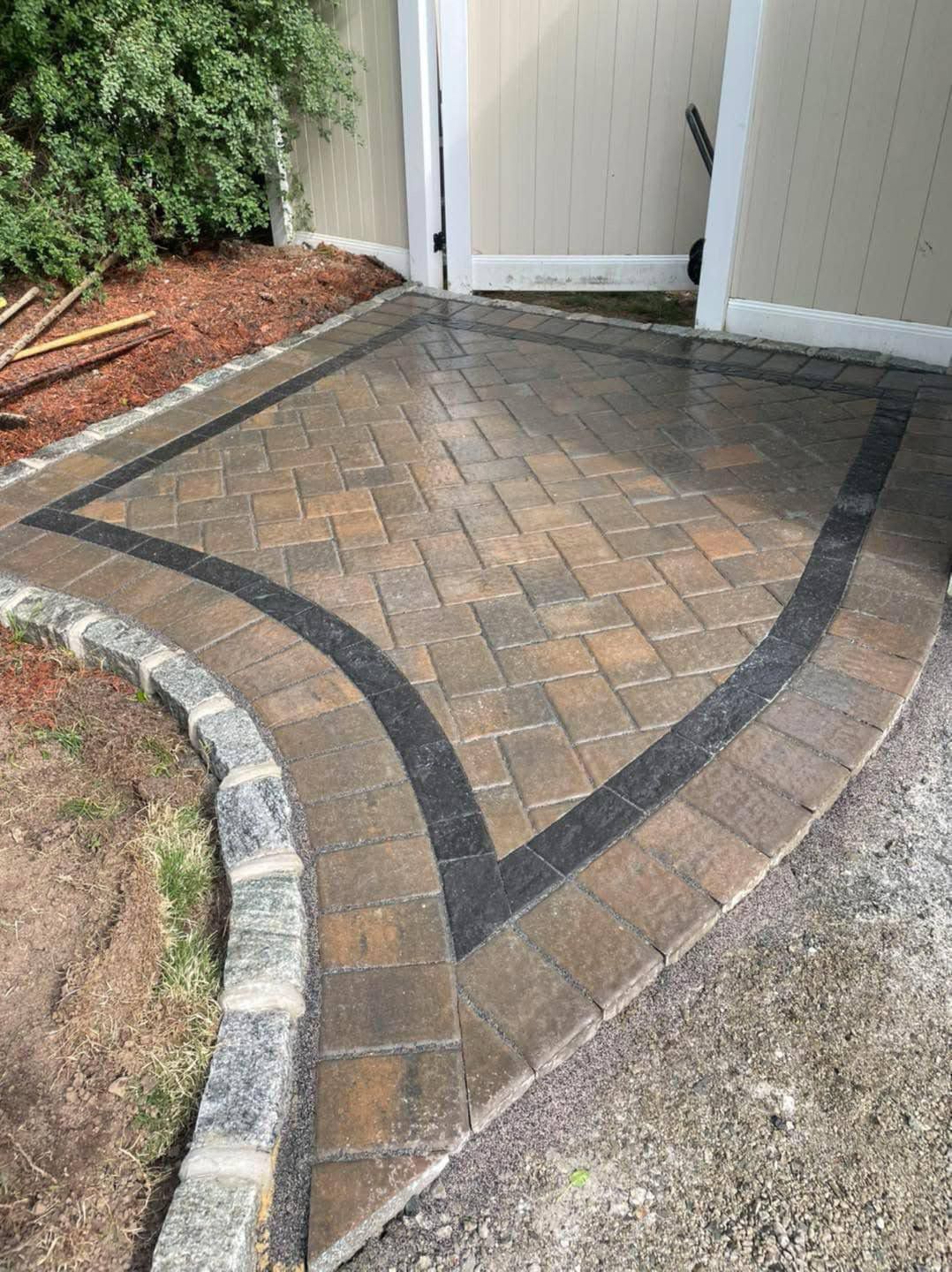 Brick paver patio with a black border, edging, and gate.