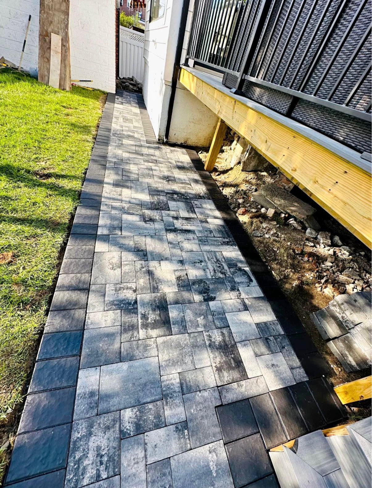 Brick path alongside grass and building with wooden supports.