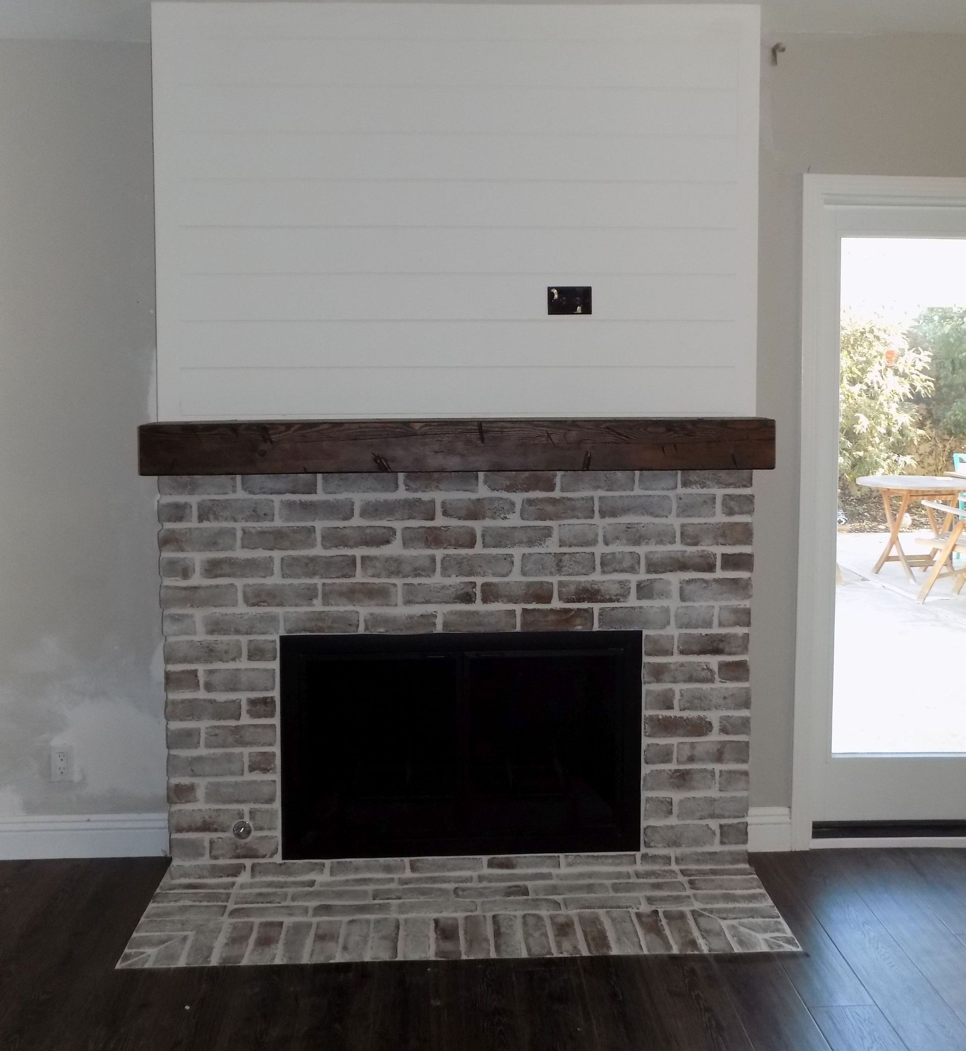 A living room with a brick fireplace and a wooden mantle.