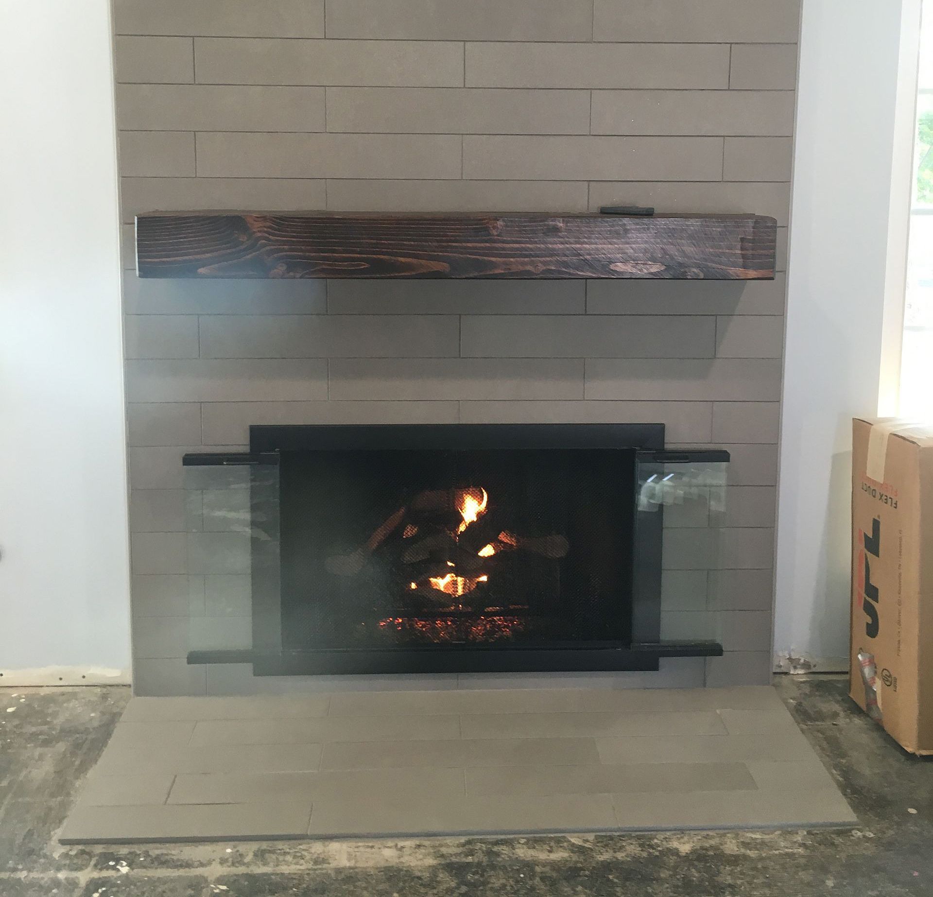 A fireplace with a glass screen and a wooden mantle.