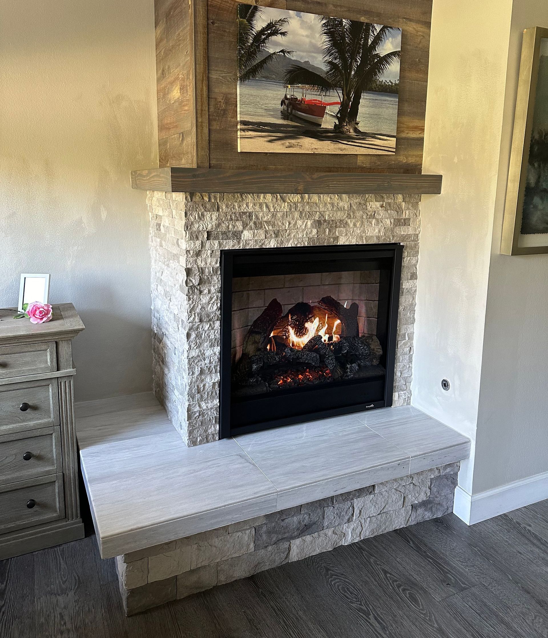 A living room with a fireplace and a painting on the wall above it.