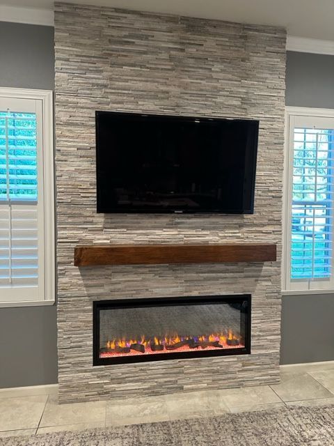 A living room with a fireplace and a flat screen TV on the wall.
