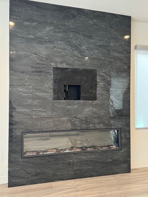 A living room with a fireplace and a flat screen TV on the wall.