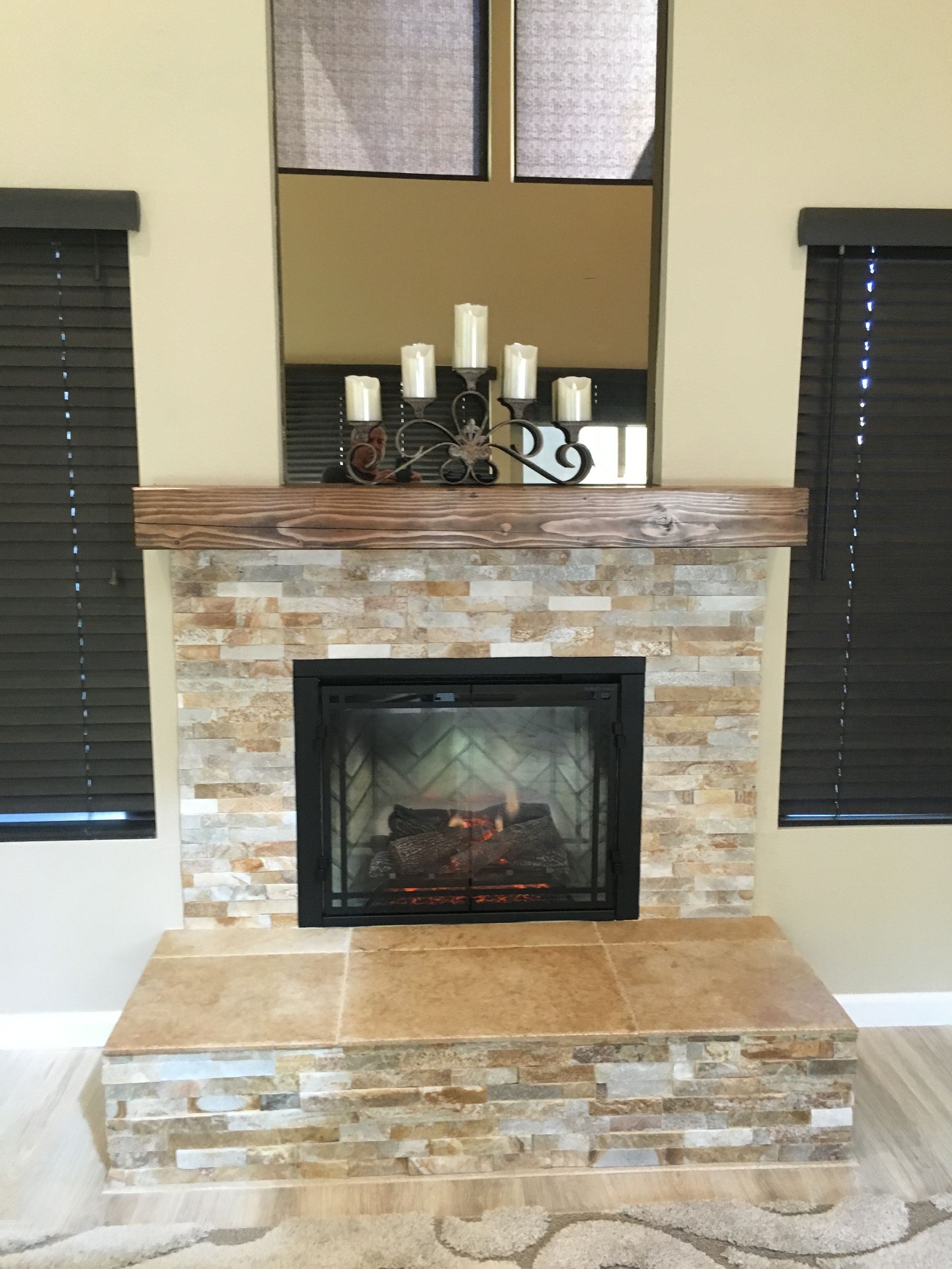 A living room with a fireplace and candles on the mantle.