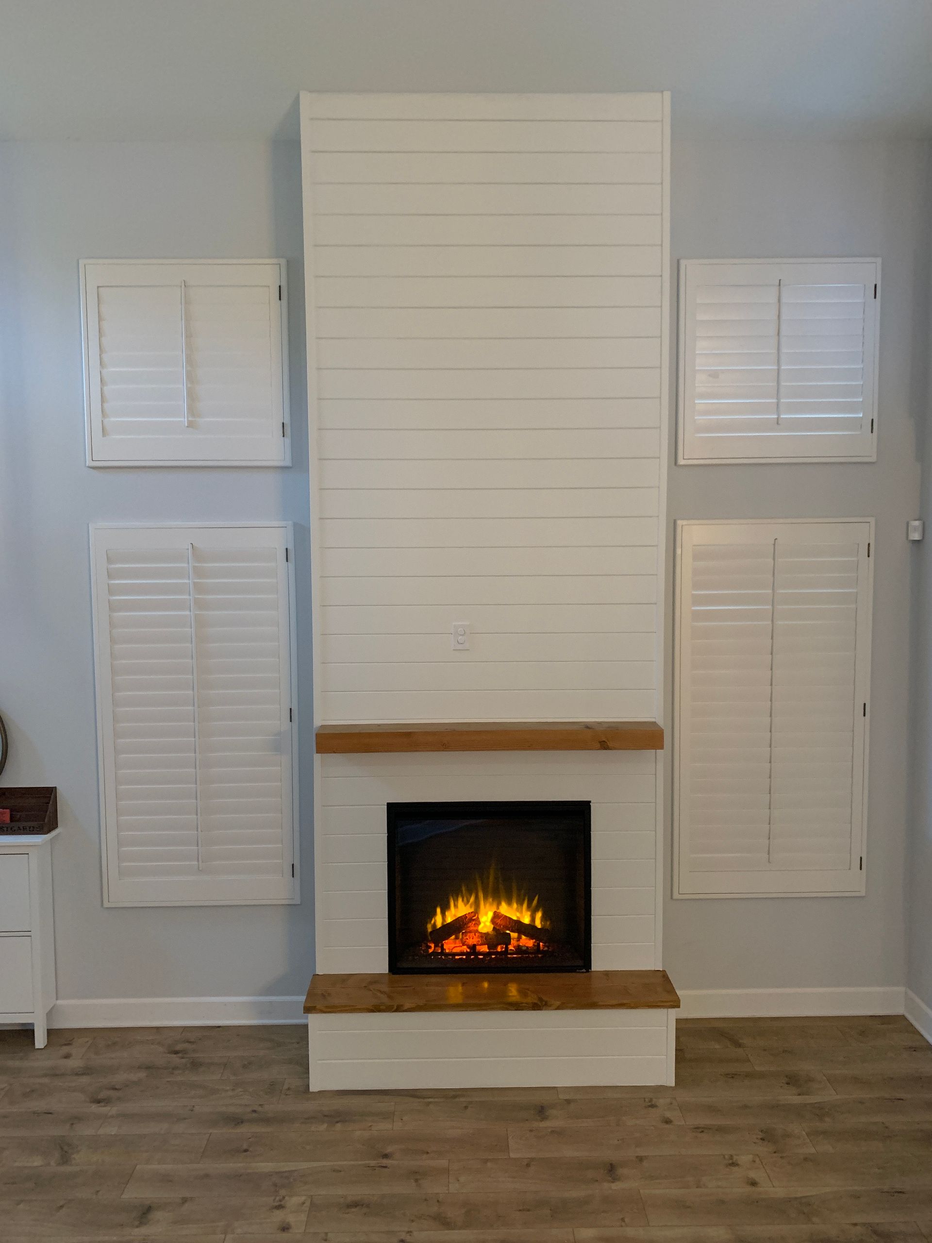 A living room with a fireplace and shutters on the wall.