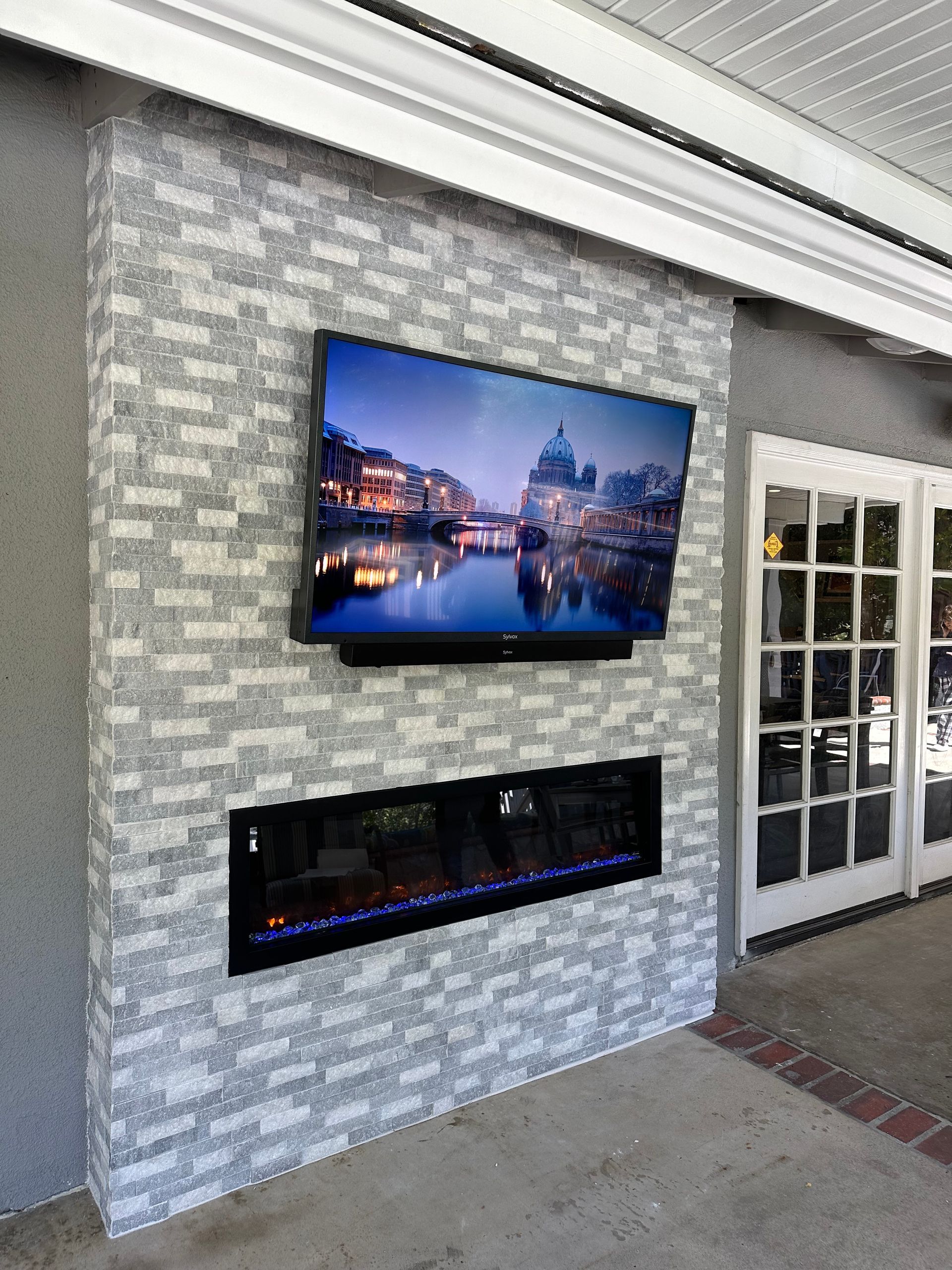 A flat screen TV is mounted on a brick wall above a fireplace.