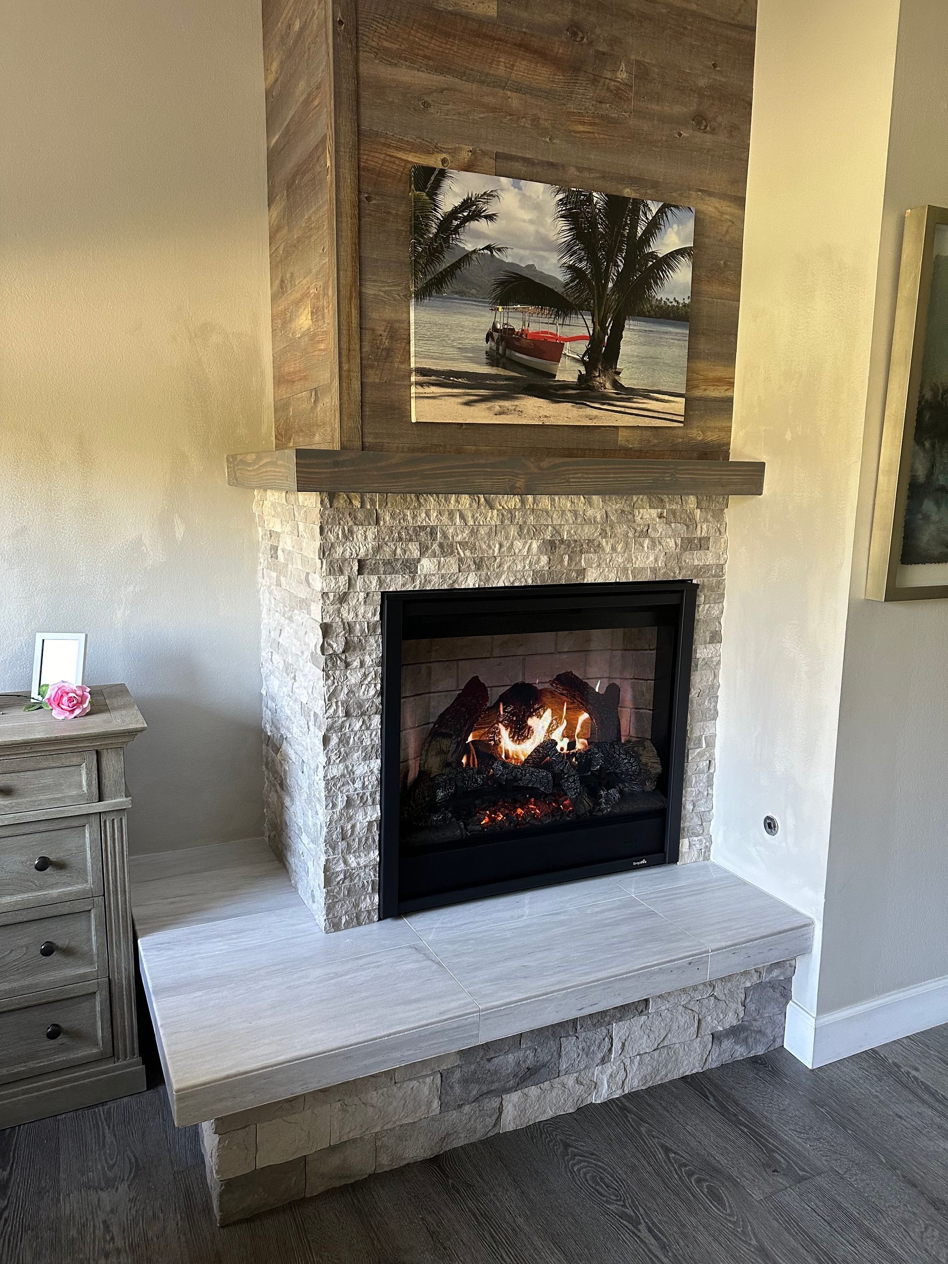 A living room with a fireplace and a picture on the wall above it.